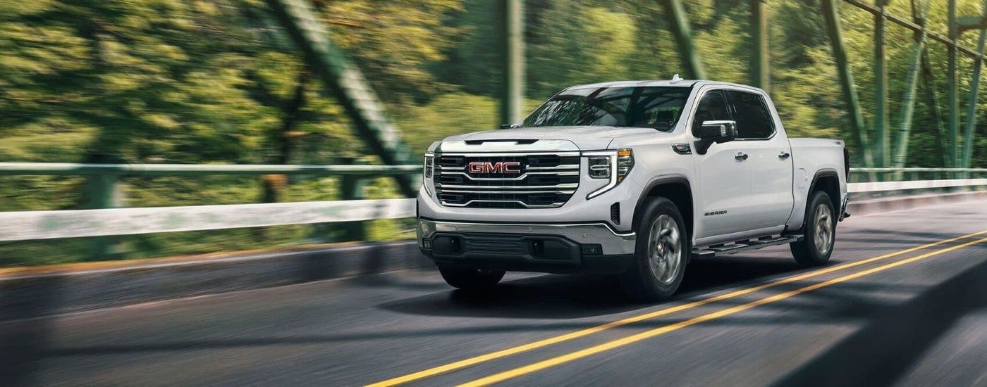 A white 2024 GMC Sierra 1500 SLE driving across a bridge.