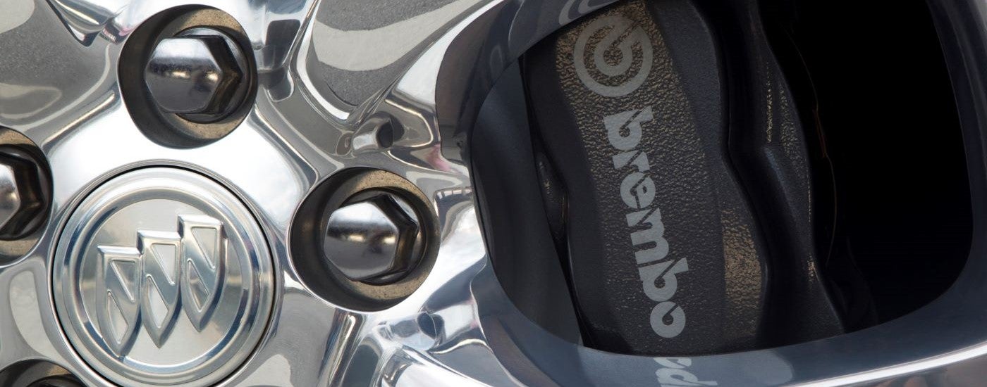 A close up shows the chrome wheel and grey Brembo caliper on a 2012 Buick Regal GS.