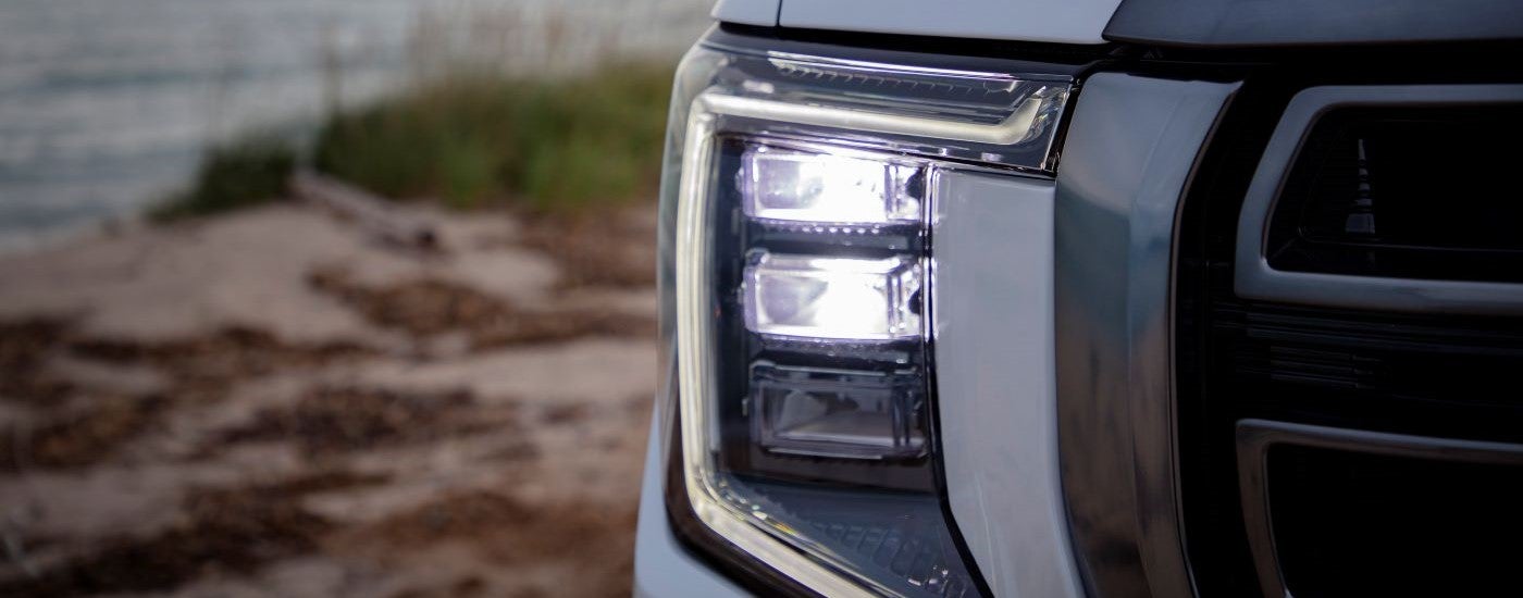 A close up shows the passenger side headlight on a white 2021 GMC Yukon AT4.